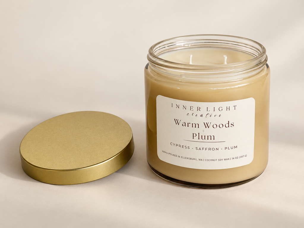 Warm Woods + Plum candle by Inner Light Creative with the lid removed, showing two wicks and a gold lid beside the oatmeal-colored jar.