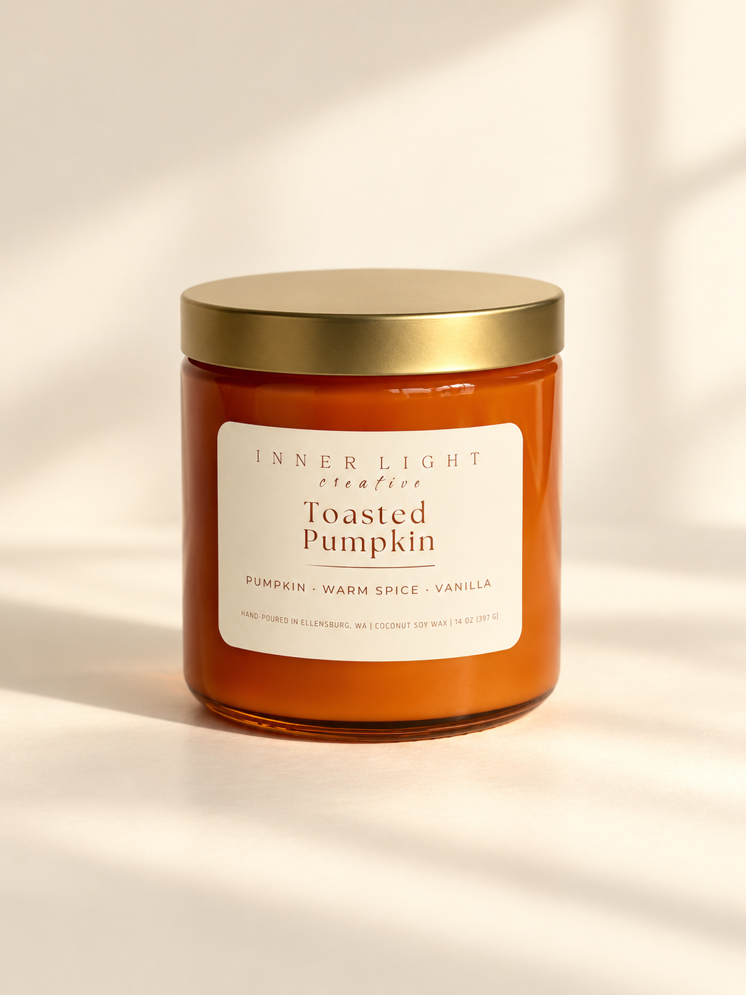 Inner Light Creative Toasted Pumpkin coconut soy candle in an orange glass jar with a gold lid and cream label.
