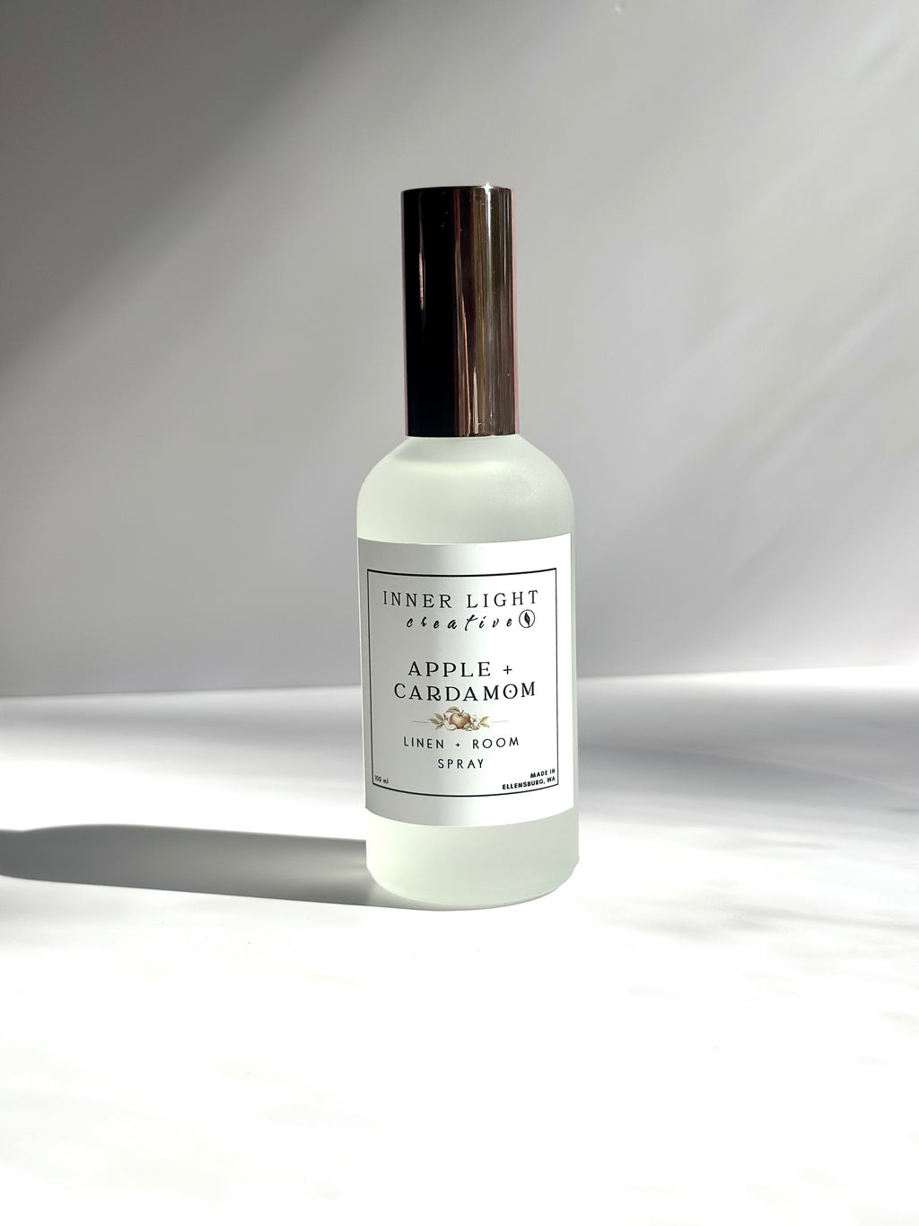Apple + Cardamom room spray in frosted glass bottle with soft natural shadows