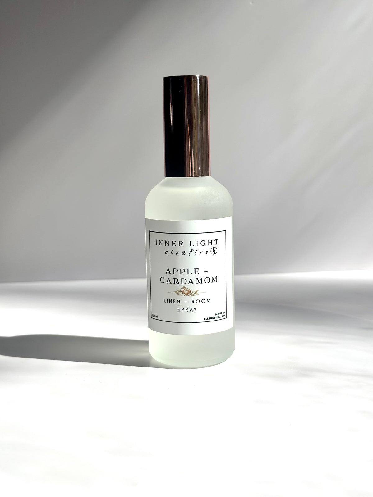 Apple + Cardamom room spray in frosted glass bottle with soft natural shadows